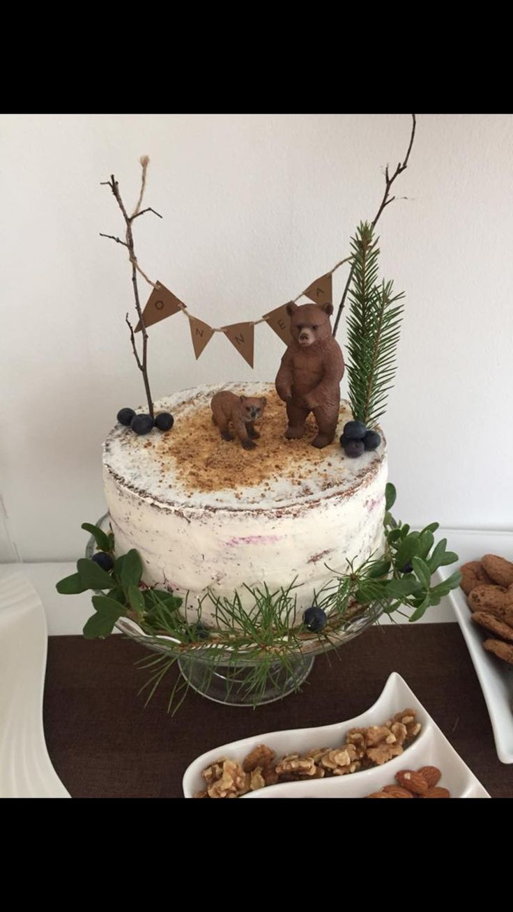 there is a cake with two bears on top and nuts in the bowl next to it