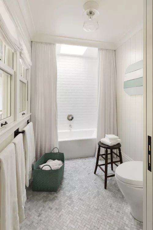 a bathroom with a tub, toilet and sink next to a white bathtub in front of a window