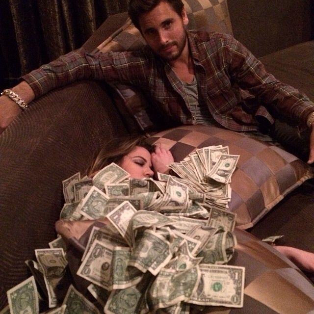 a man and woman laying on top of a couch covered in money with the caption he she's using cash