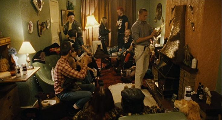 a group of people sitting in a living room next to a fire place with guitars