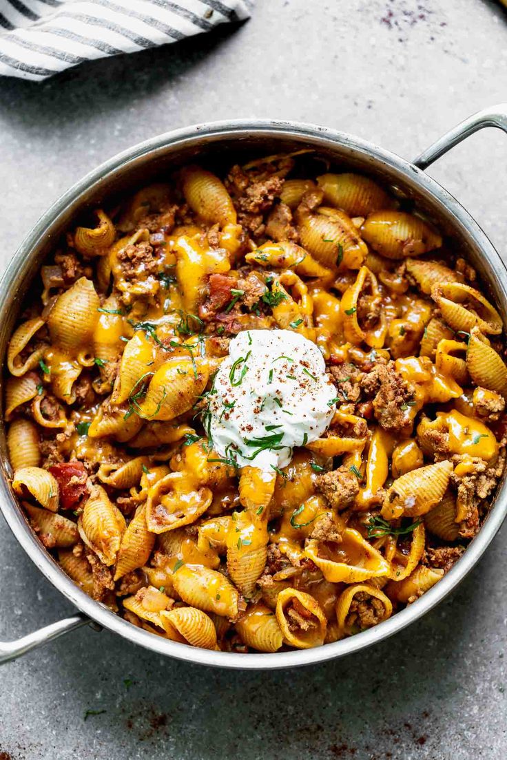 a pot full of pasta with meat and cheese on the top, next to a striped towel