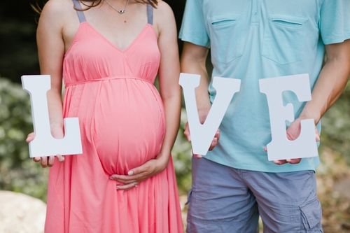 a pregnant couple holding the word love in front of them