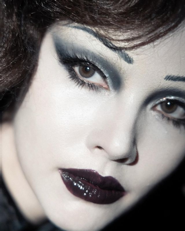 a woman with black and white makeup is posing for the camera while wearing dark eyeliners