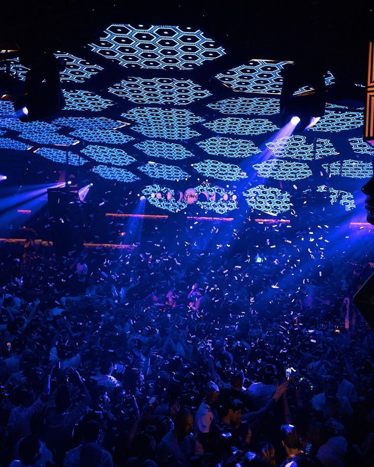 a large group of people at a concert with lights and confetti on the ceiling