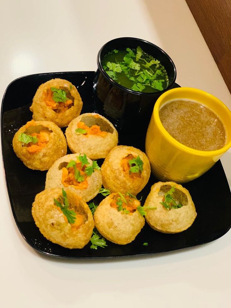 small appetizers on a black plate with dipping sauce