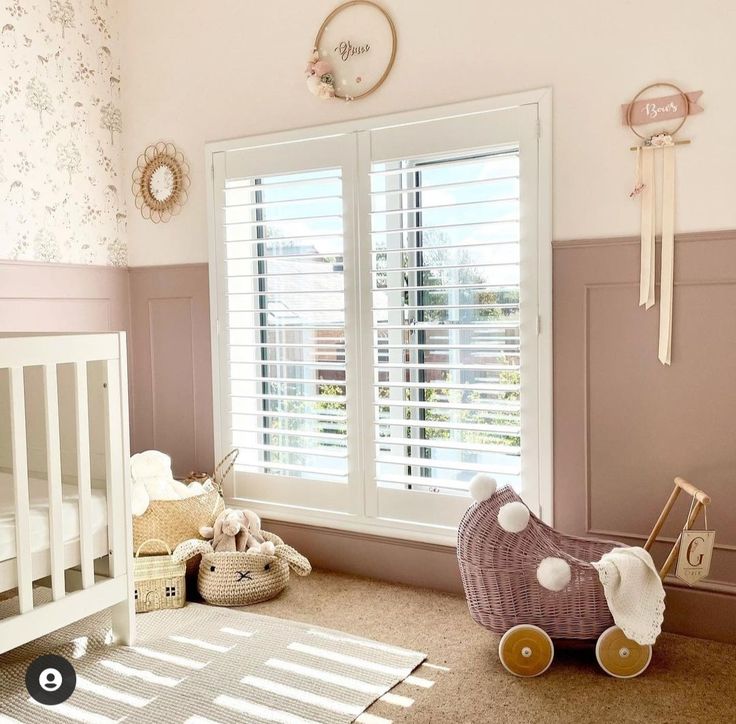 a baby's room with pink walls and white shutters