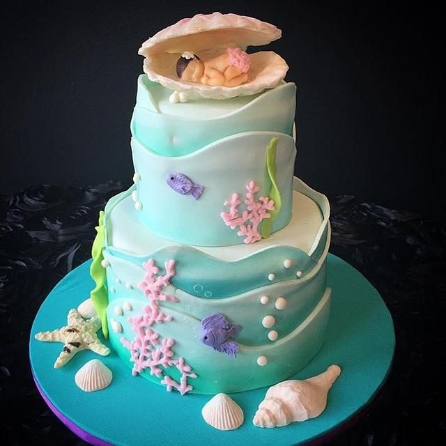 a three tiered cake decorated with sea animals and seashells on a blue plate