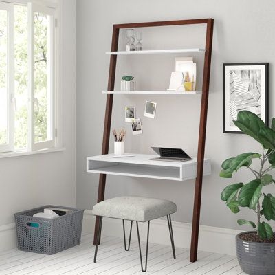 a desk and chair in a room next to a potted plant on the floor