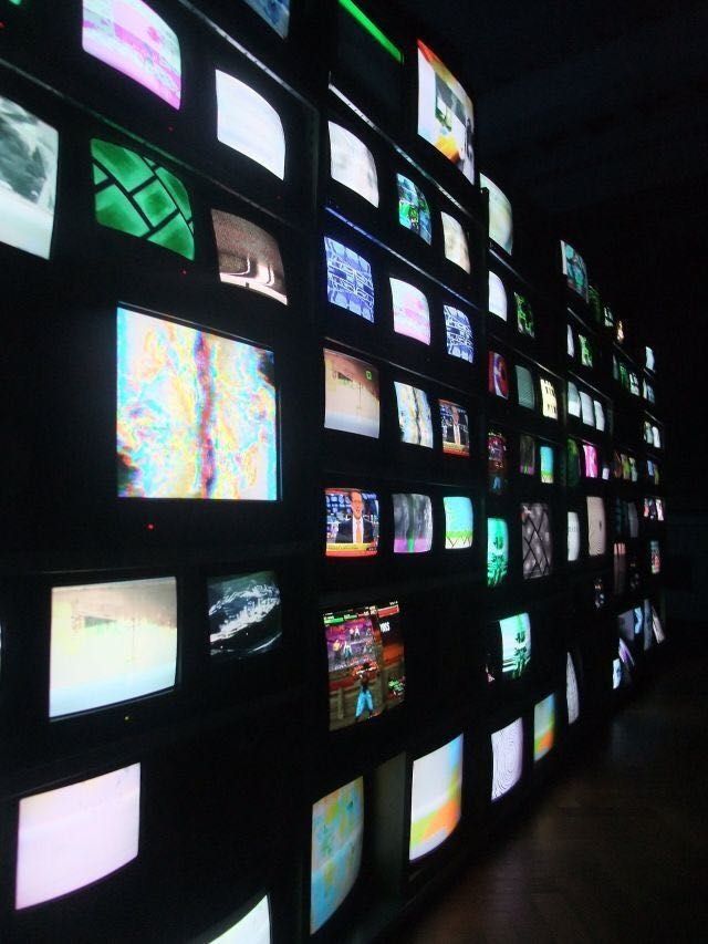 many televisions are shown on the wall in this dark room with no one around them