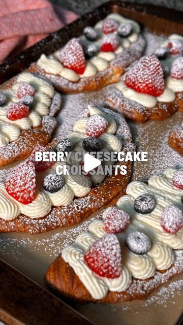 berry cheesecake croissants with cream and powdered sugar are on a baking sheet