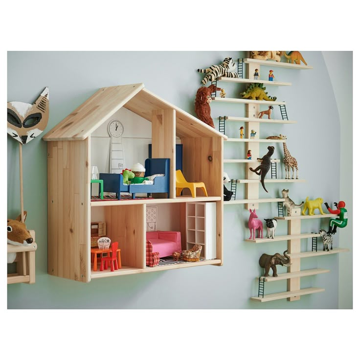 a wooden doll house with shelves and toys on the wall in front of blue walls