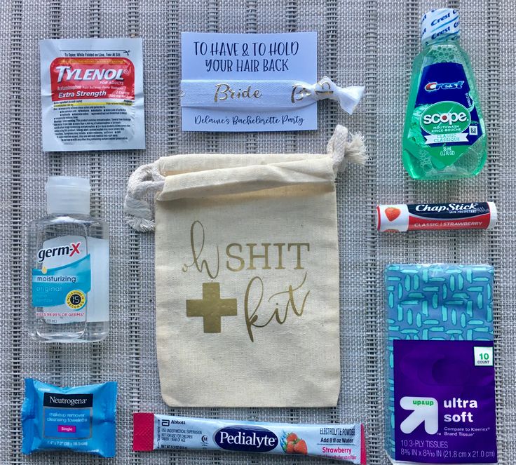 the contents of a personal care kit laid out on a woven tablecloth, including toothpaste, mouthwashes, and hand sanitizers