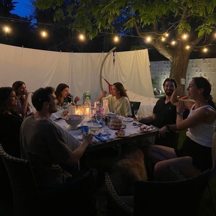 a group of people sitting around a table with food and drinks in front of them