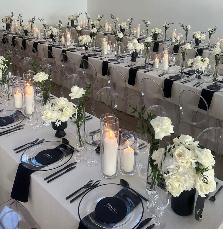 the table is set with white flowers, candles and place settings for an elegant dinner