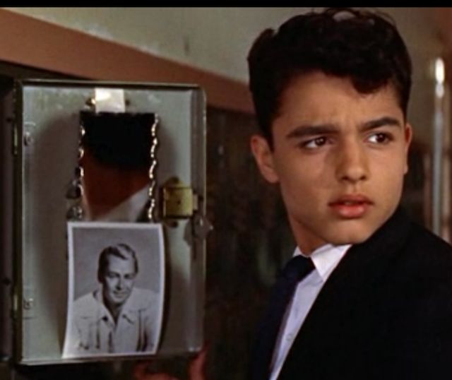 a young man in a suit and tie holding up a box with an image on it