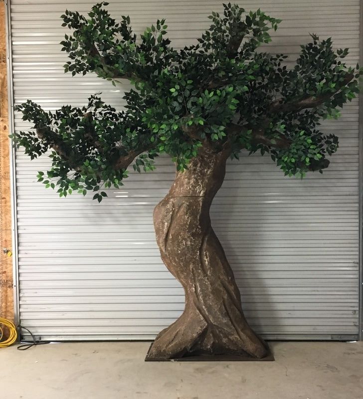 a tree that is sitting in the middle of a floor next to a garage door