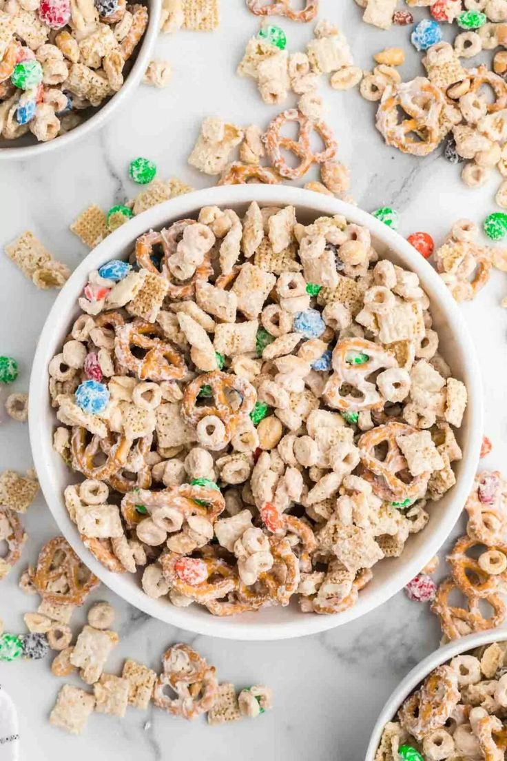 two bowls filled with lucky charms cereal on top of a white counter next to candy