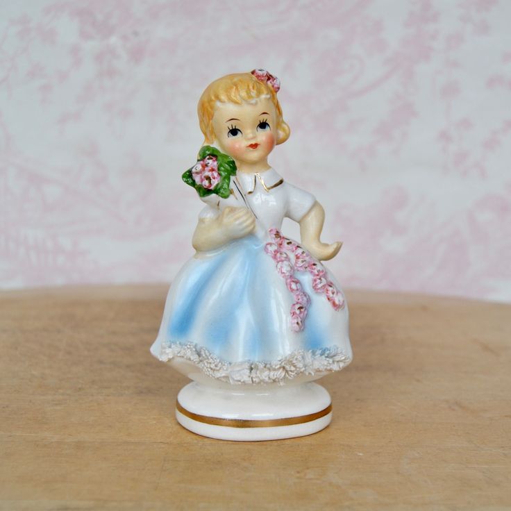 "This vintage figurine is lovely! Made of ceramic, it features a blonde girl holding a flower bouquet, there are flowers on her skirt and in her hair, there's spaghetti trim along the front of the skirt, and gold-painted accents.  Measures just under 2.75\" long x 2.15\" wide x 4.5\" high.  Maker : Made in Japan.  Time Period : 1950's. Condition : Good.. There is crazing throughout the entirety of the figurine, light paint wear, light wear on the spaghetti trim, and light dirt wear on the 'skin. Girl With Flower Bouquet, Holding A Flower, Dog Brooch, Vintage Headbands, Ceramic Figurine, Vintage Souvenir, Vintage Dog, Ceramic Figurines, Light Painting