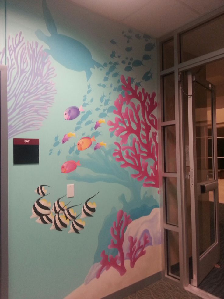 an office wall painted with sea life and corals on the walls, along with glass doors