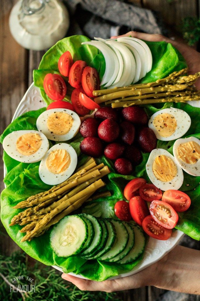 a plate filled with lettuce, tomatoes, cucumbers and hard boiled eggs