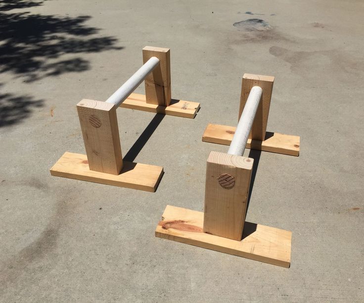 three pieces of wood with two white pipes on each end and one is standing in the middle