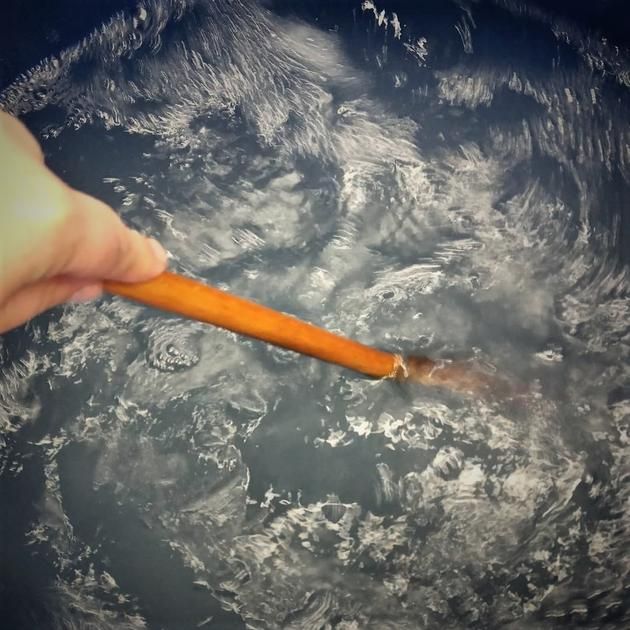 a person holding a carrot in the middle of a frying pan filled with water