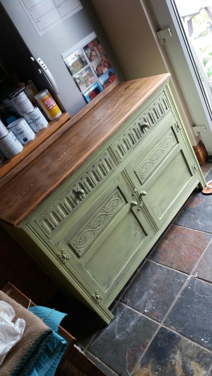 a green cabinet sitting in front of a window next to a floor covered with dirt