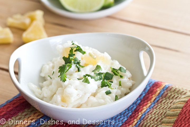 a white bowl filled with rice and garnished with parsley next to lime wedges