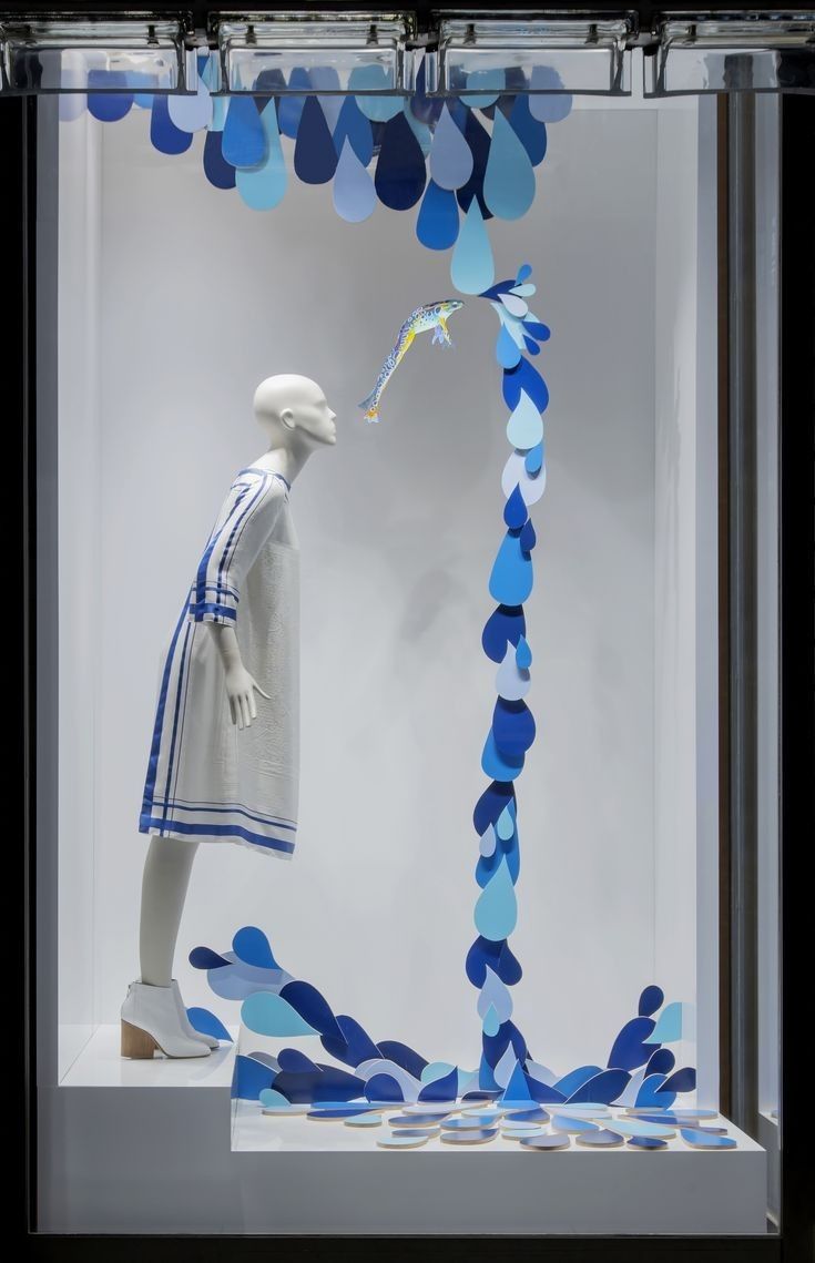 a white mannequin in a glass case with blue confetti streamers