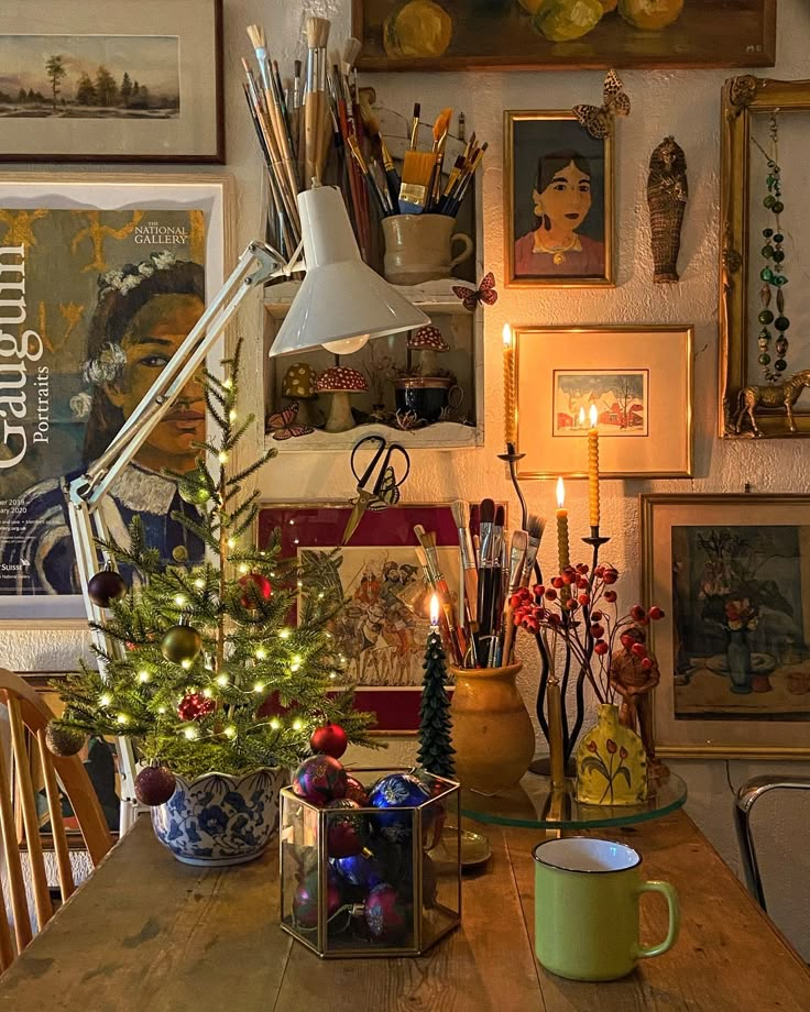 a wooden table topped with a christmas tree next to a wall covered in framed pictures