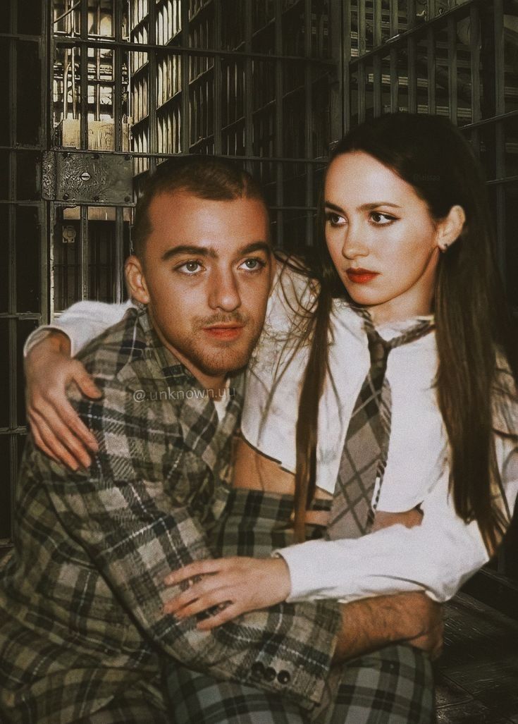 a man and woman sitting next to each other in front of jail cell doors with their arms around each other