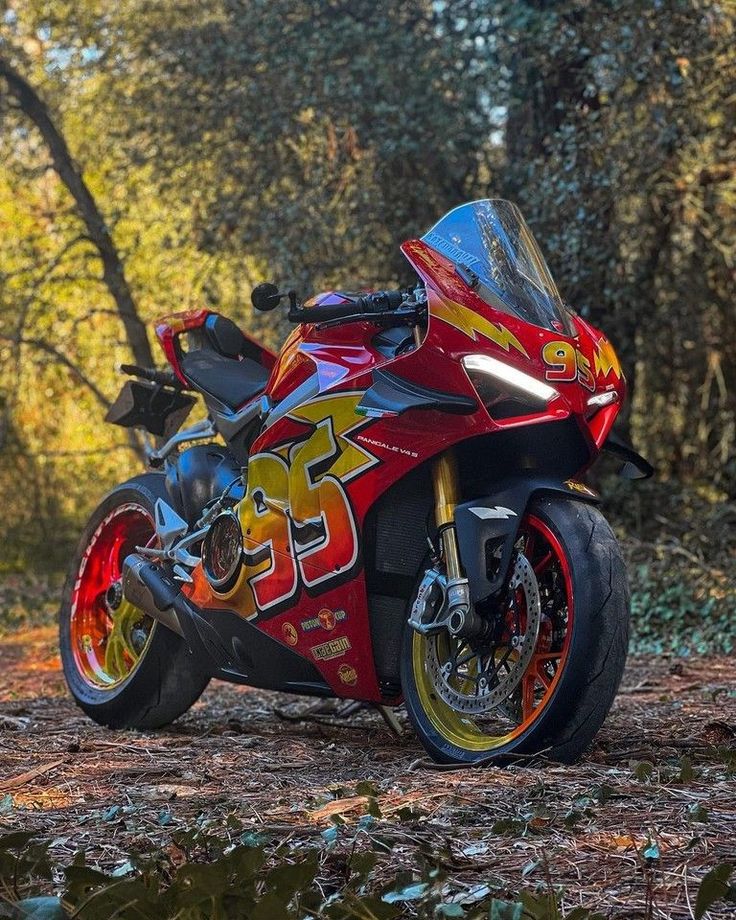 a red and yellow motorcycle parked in the woods