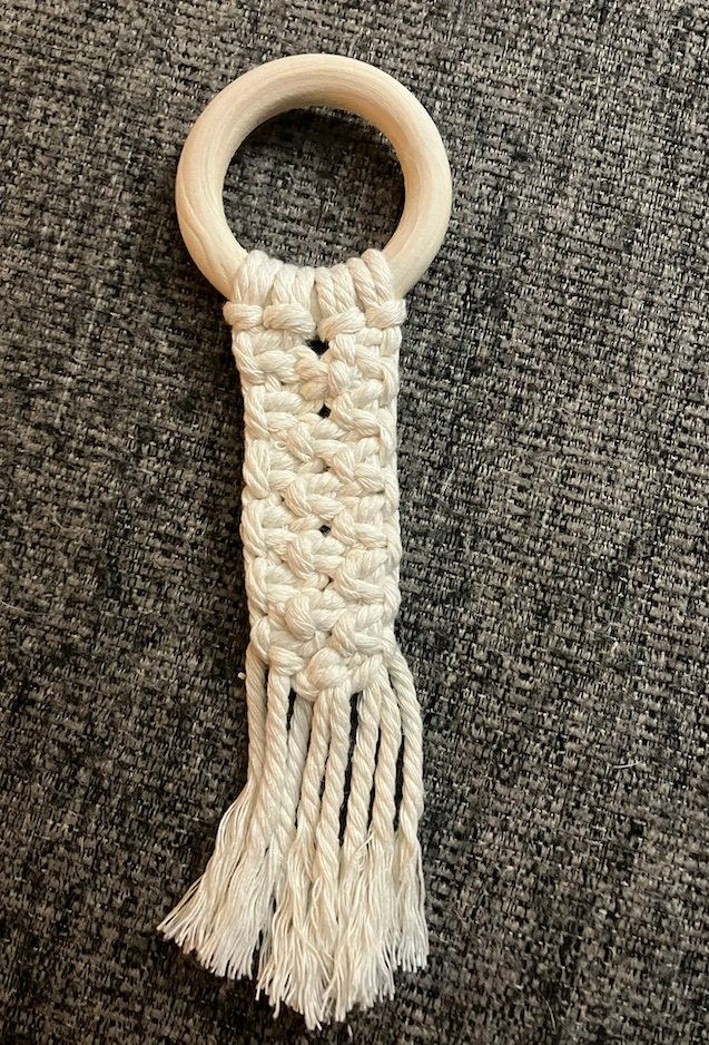 a piece of wood and rope hanging from a hook on a carpeted area with gray fabric