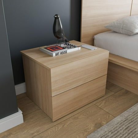 a nightstand with a book on it next to a bed