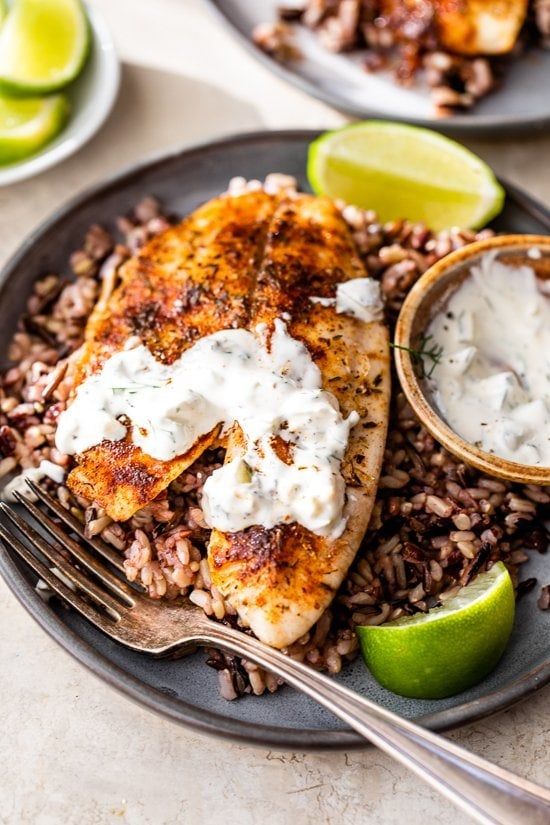 a plate topped with rice and chicken next to lime wedges on top of a table