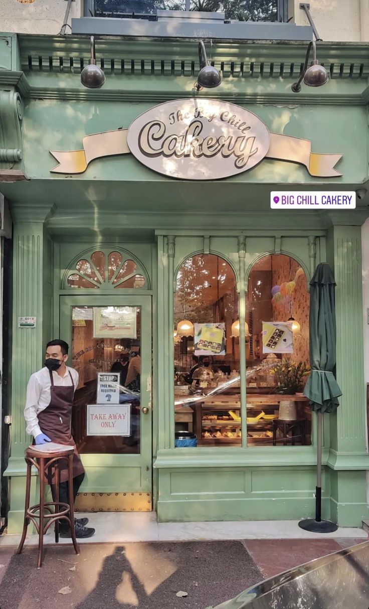 a man sitting at a table in front of a bakery