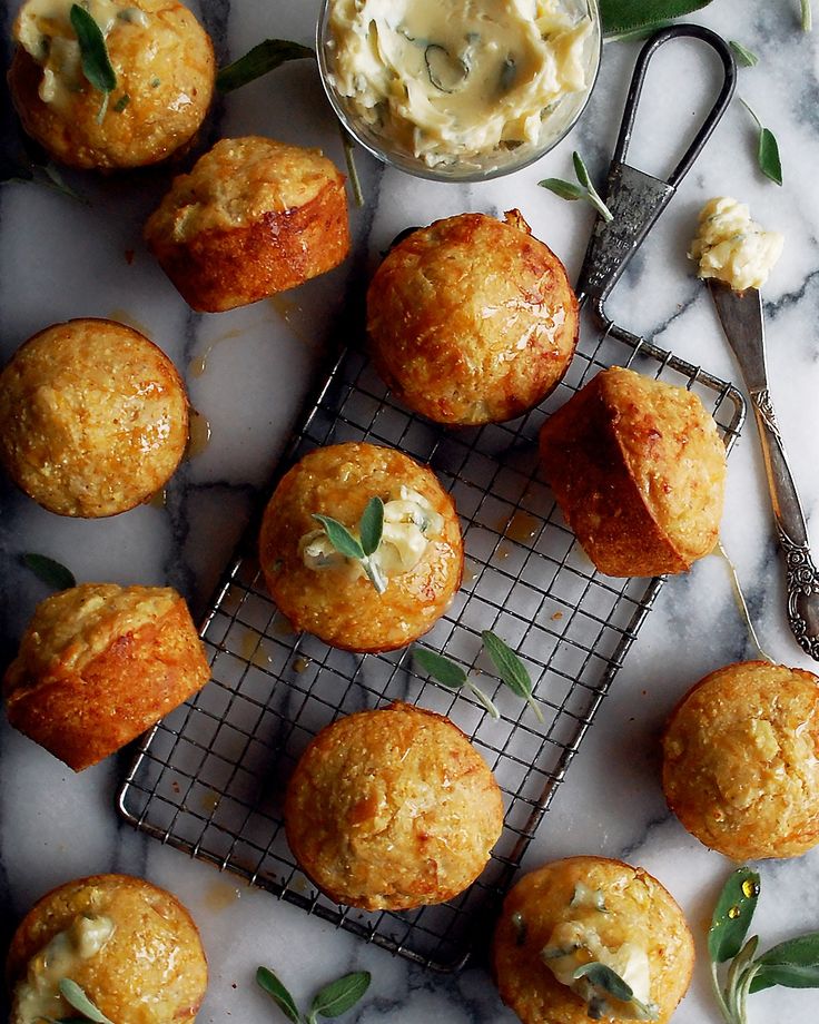 several muffins on a cooling rack with butter and herbs