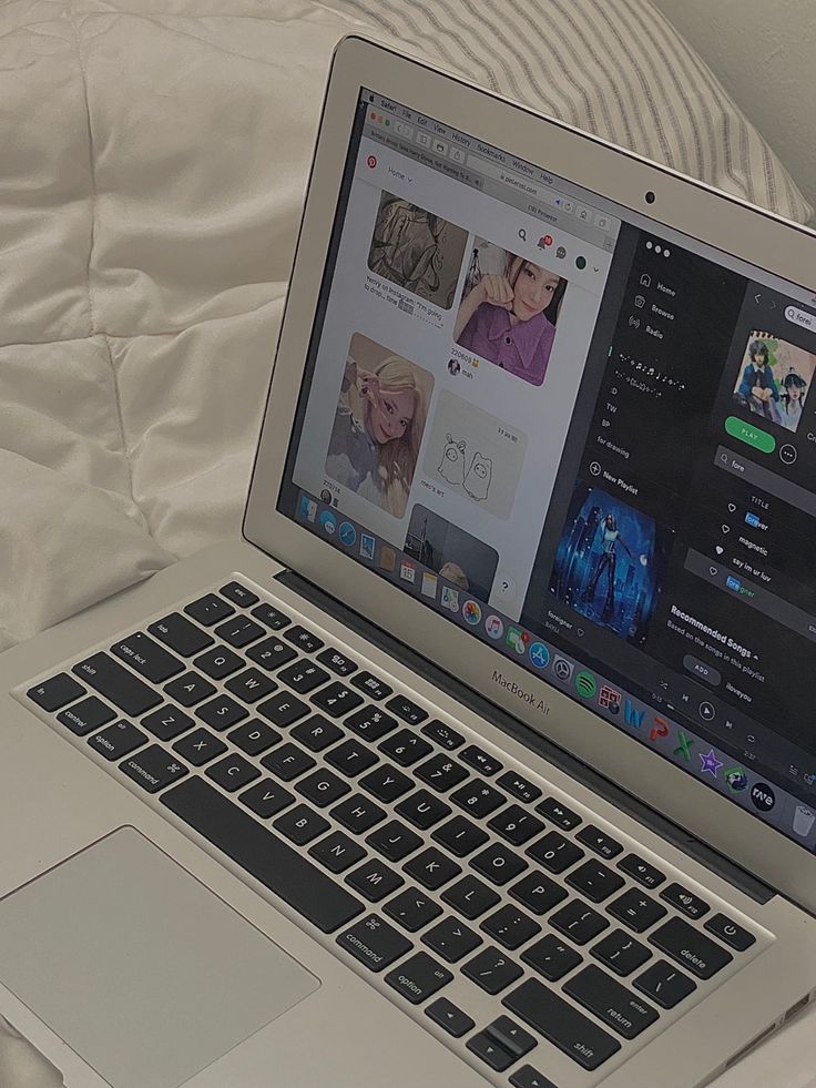 an open laptop computer sitting on top of a white bed covered in sheets and pillows