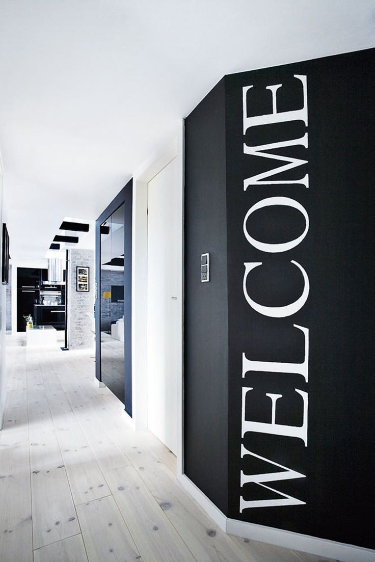 a black and white hallway with the words welcome written on the wall next to it