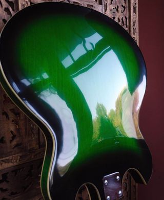 a green and black guitar is hanging on the wall