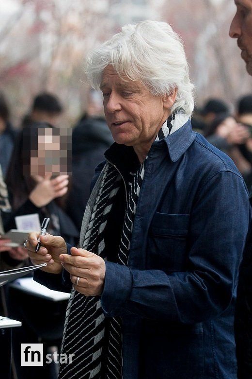 an older man is writing something on his clipboard while others are standing in the background