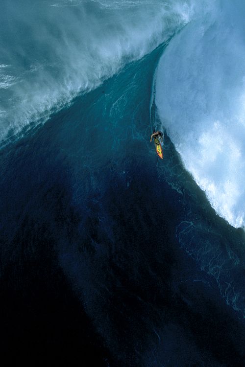 a man riding a wave on top of a surfboard in the middle of an ocean