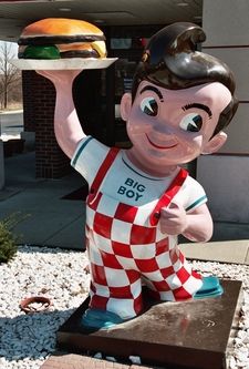 a statue of a man with a hamburger in his hand and holding it up to the side