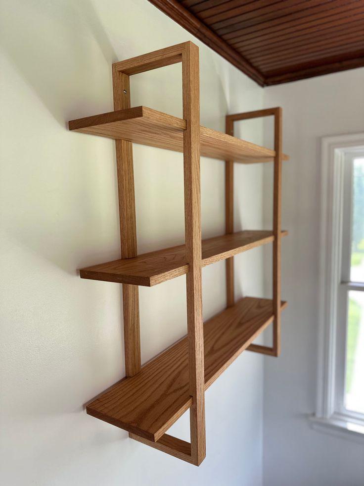 a wooden shelf hanging from the side of a wall in a room with white walls