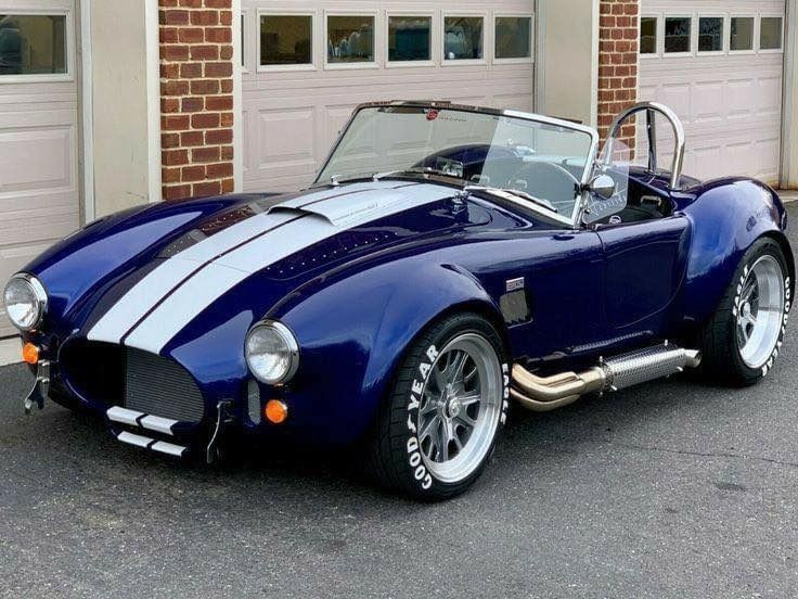 a blue and white striped sports car parked in front of a garage with two doors