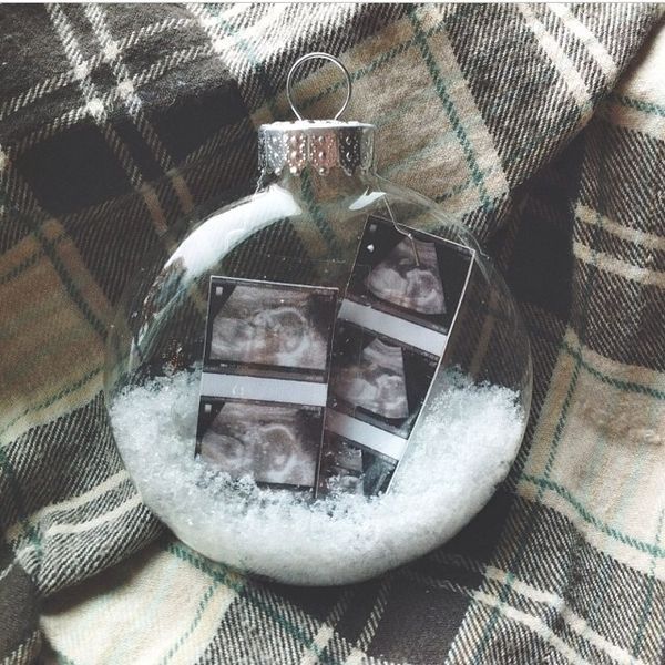 a glass ornament with two photos in it on a plaid blanket and snow