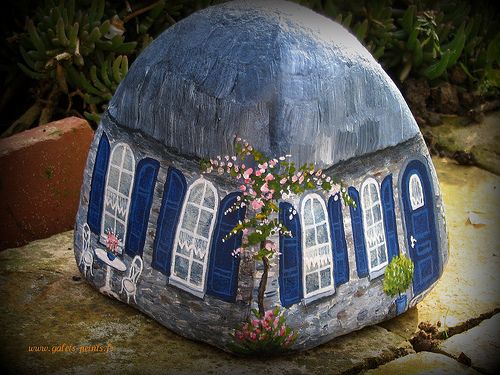 a painted rock house with blue shutters and windows