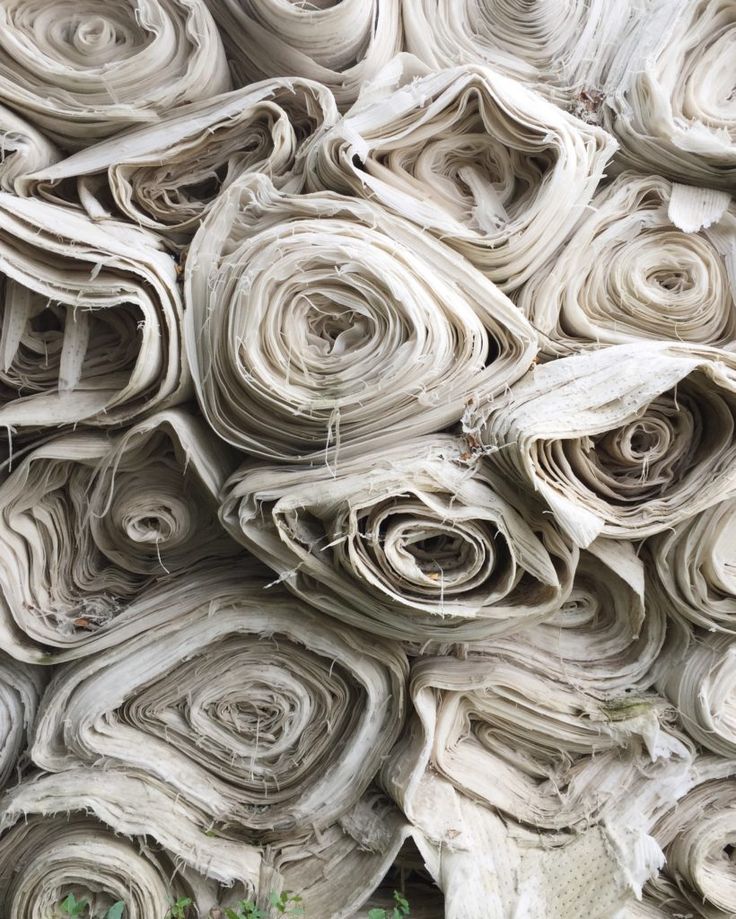 many rolled up papers are stacked on top of each other in order to be used as wall art