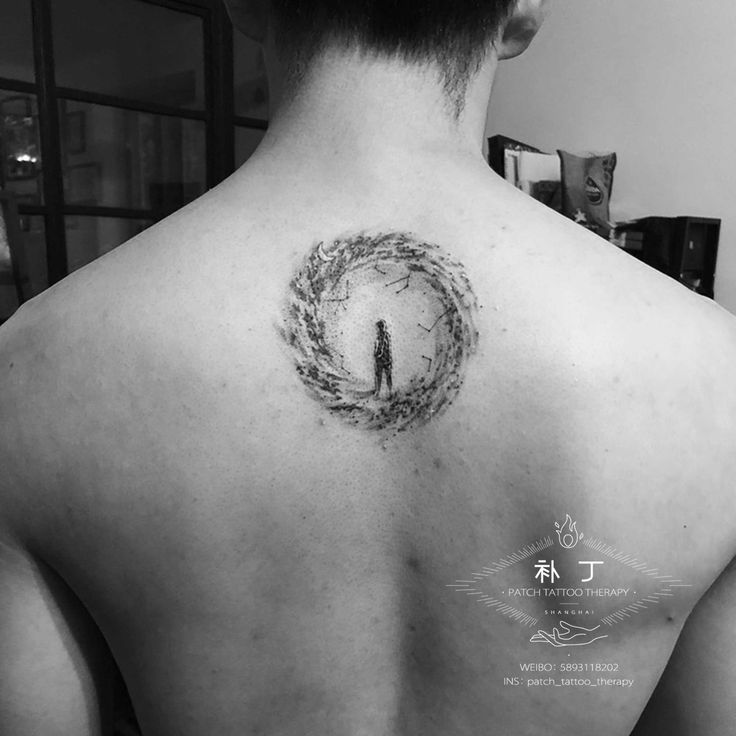 the back of a man's neck with a circle tattoo on his left shoulder