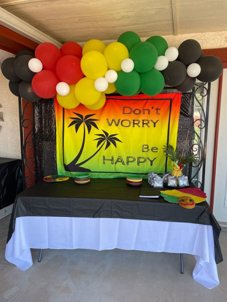 a table topped with balloons and a sign that says don't worry be happy